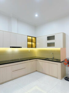 Thi công mẫu tủ bếp chữ L hiện đại PVC012 kết hợp cánh acrylic bóng gương và tủ trang trí kính